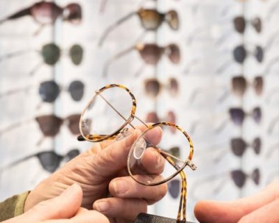 Brille wird von einer Hand gehalten.